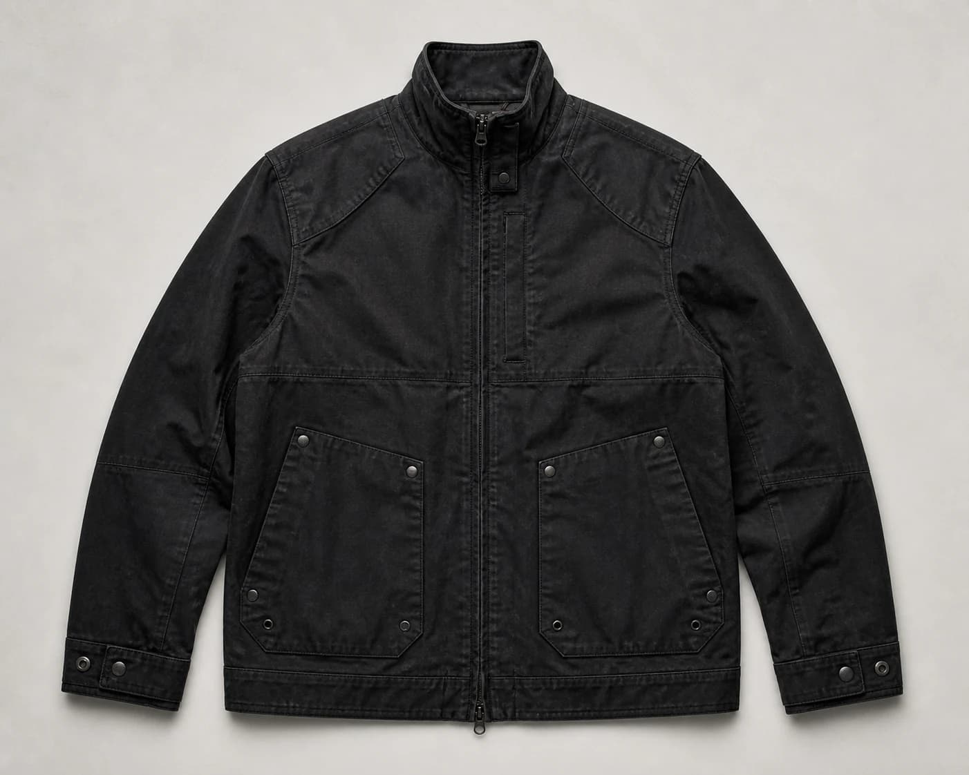 Black field jacket laid flat with its seams and hardware visible