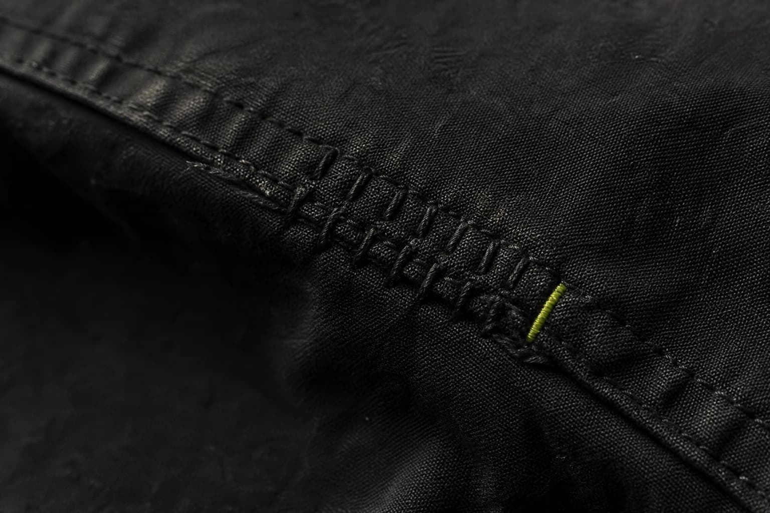 Close view of black fabric reinforced with careful repair stitches