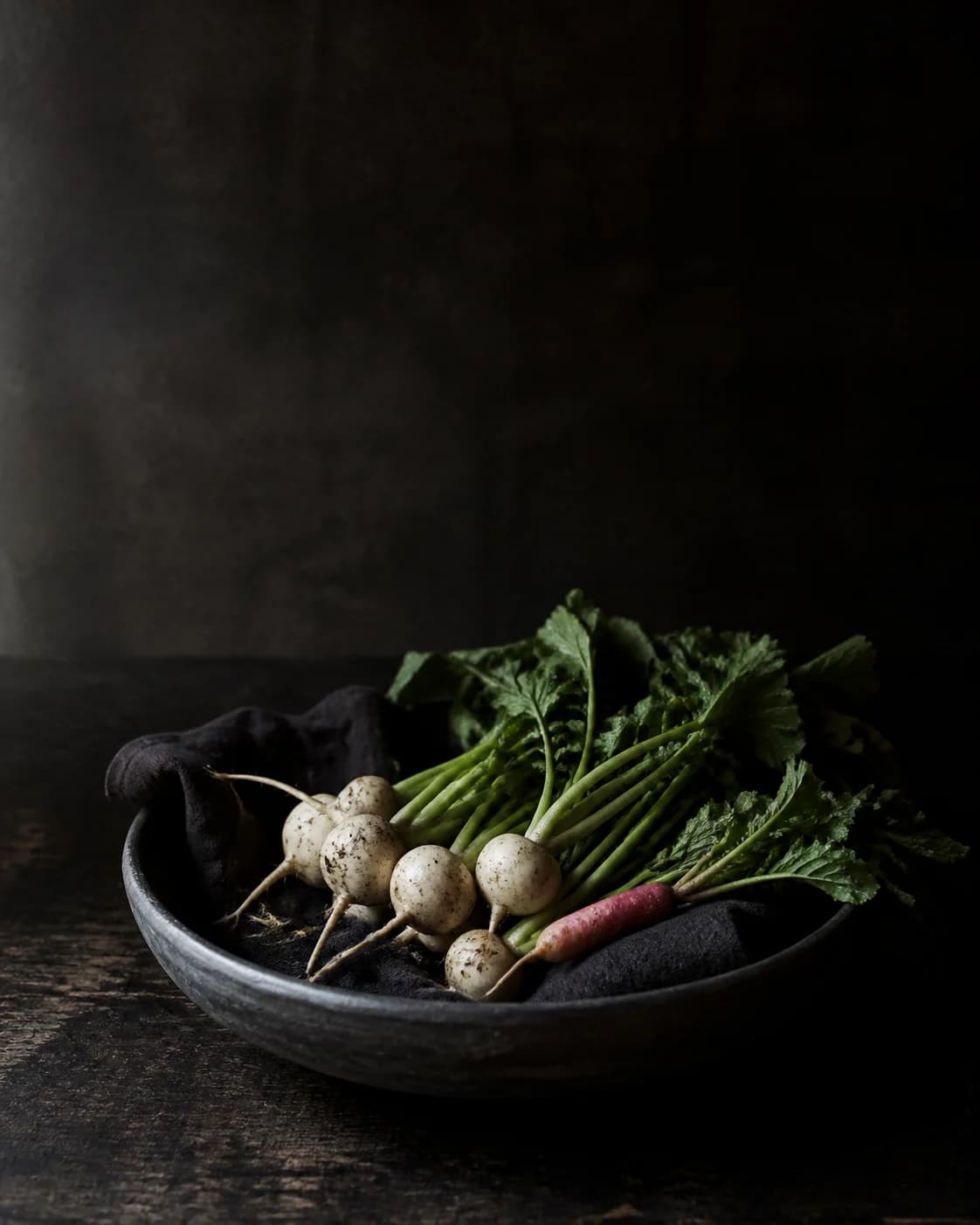 Freshly harvested turnips in a dark ceramic bowl